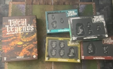 A photo of the Epic Encounters: Local Legends Tavern Kit and four encounter boxes sitting on a gaming mat.